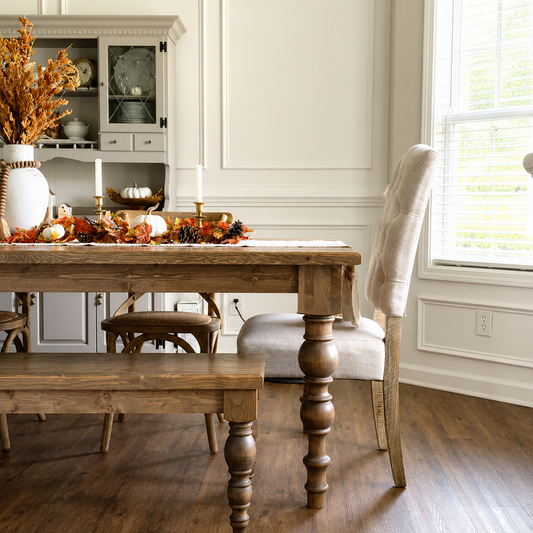 Dining room with wooden table and chairs, autumn decorations, and a window.